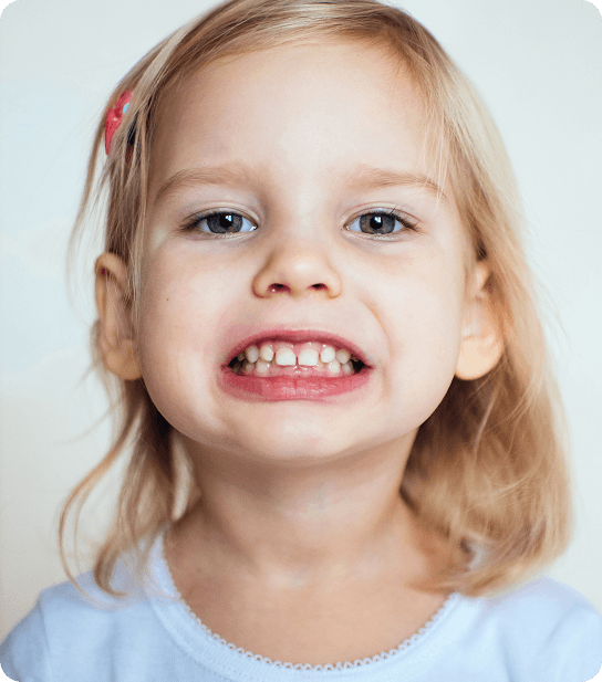 Young child smiling and showing healthy teeth