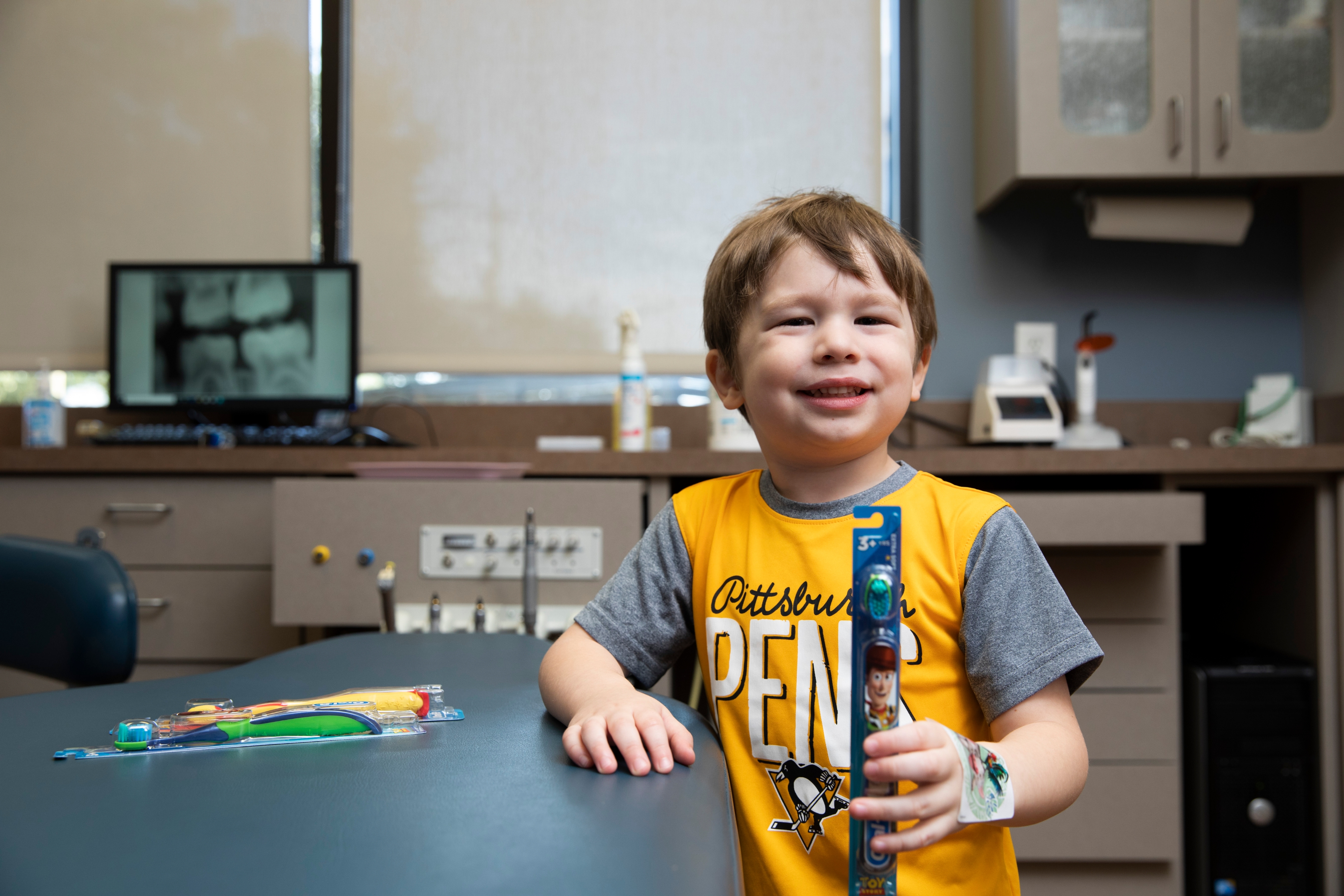 A young patient holding a new toothbrush at Big Picture Pediatric Dentistry