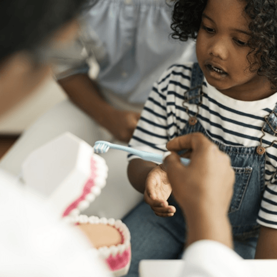 A child learning about dental care with a model